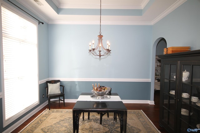 dining area with a raised ceiling, dark hardwood / wood-style floors, and ornamental molding