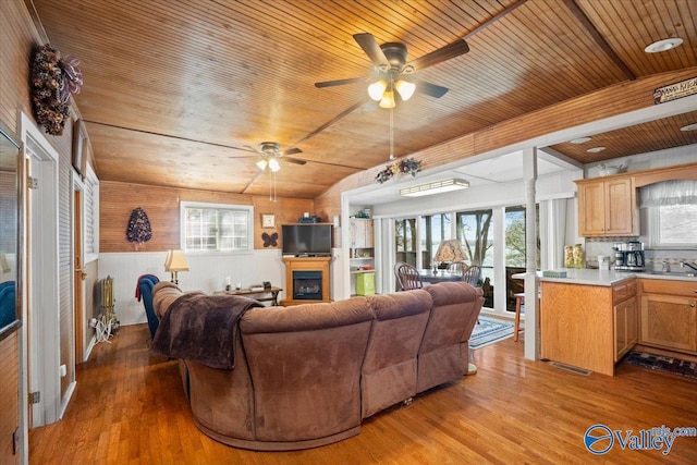 living room with light hardwood / wood-style flooring, wood ceiling, and a wealth of natural light