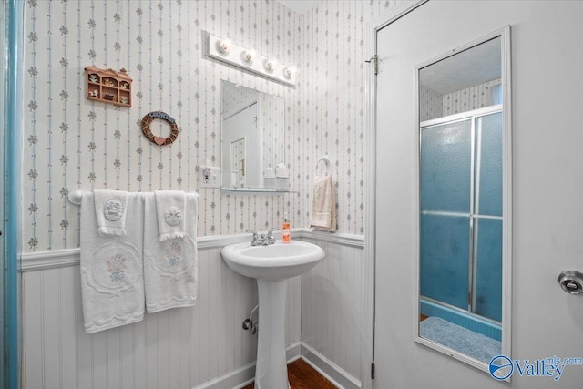 bathroom with sink and a shower with door