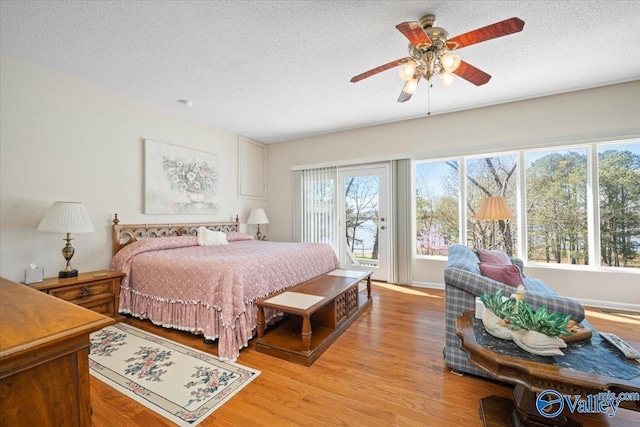 bedroom featuring a textured ceiling, access to outside, and light hardwood / wood-style floors