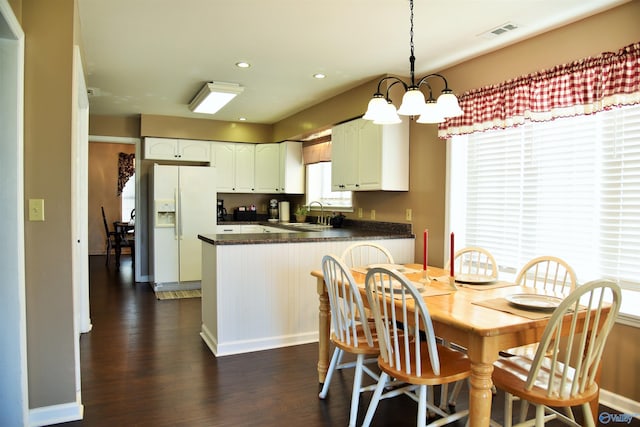 dining room with a notable chandelier, sink, and dark wood-type flooring