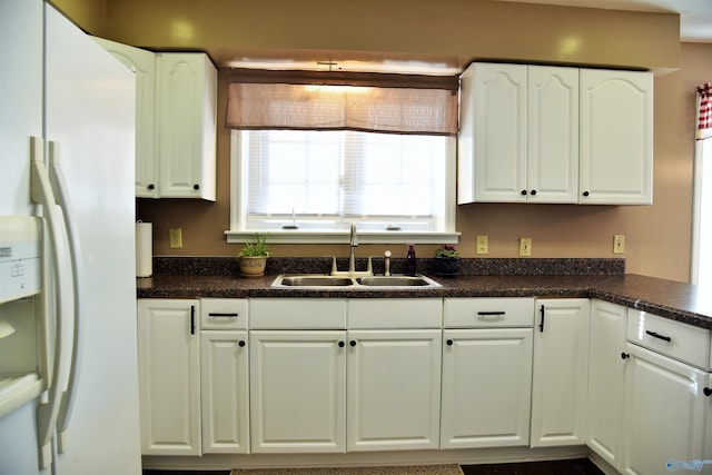 kitchen with white refrigerator with ice dispenser, white cabinets, and sink