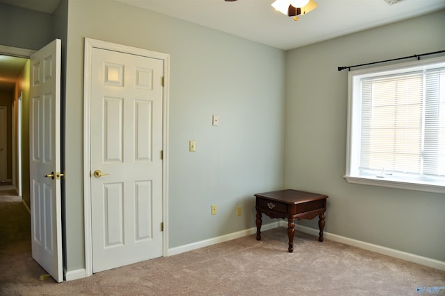 interior space featuring ceiling fan, light colored carpet, and multiple windows