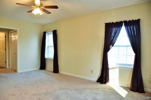 carpeted spare room featuring a wealth of natural light and ceiling fan