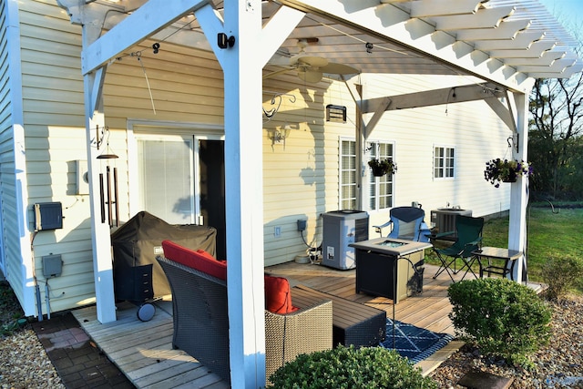 wooden terrace featuring ceiling fan, central AC unit, and a fire pit