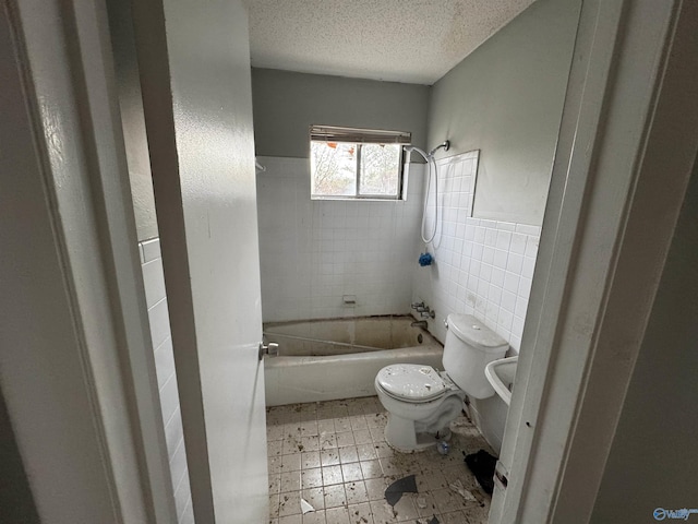 bathroom featuring shower / tub combination, a textured ceiling, toilet, and tile walls