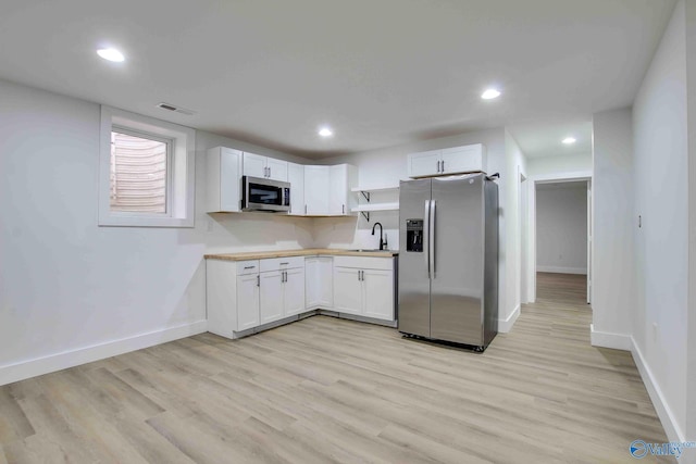 kitchen featuring white cabinetry, sink, appliances with stainless steel finishes, and light hardwood / wood-style flooring