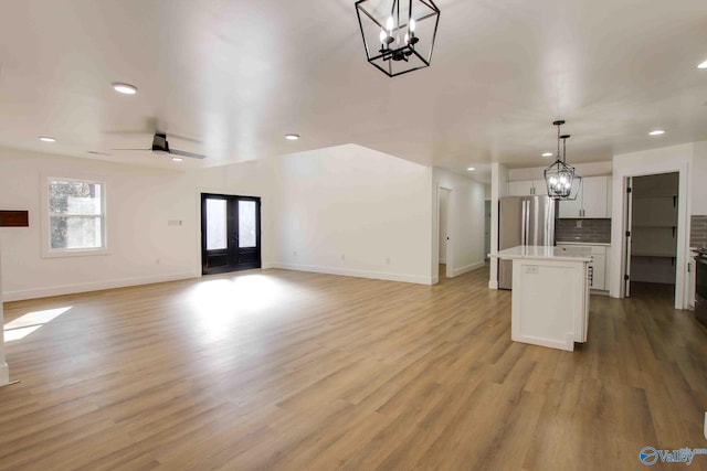 unfurnished living room with ceiling fan, french doors, and light hardwood / wood-style flooring