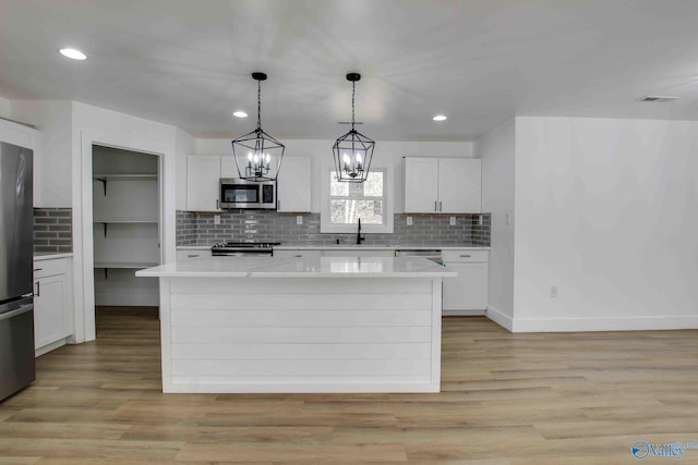 kitchen featuring white cabinetry, a center island, light hardwood / wood-style floors, and appliances with stainless steel finishes