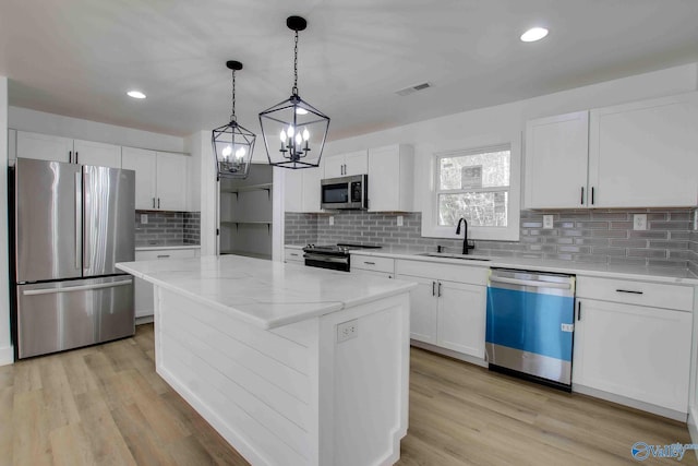 kitchen with white cabinetry, a center island, stainless steel appliances, and sink