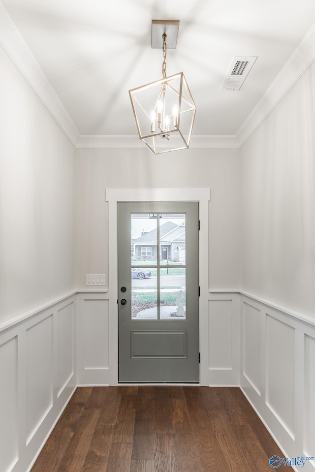 doorway to outside featuring crown molding, dark wood-type flooring, and an inviting chandelier