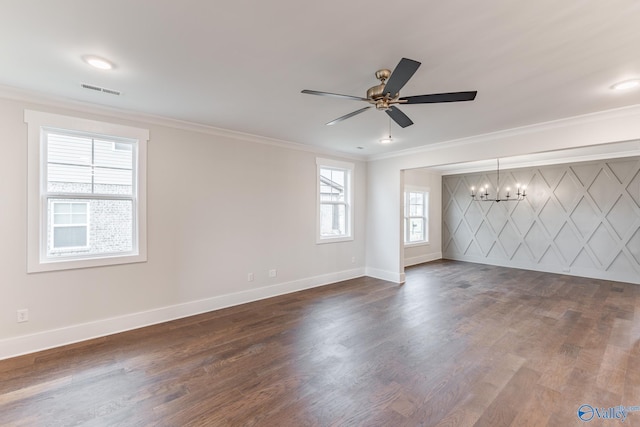 empty room featuring ornamental molding, dark hardwood / wood-style floors, ceiling fan with notable chandelier, and plenty of natural light