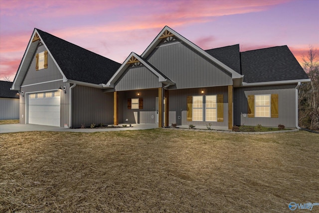 view of front of house featuring a yard, roof with shingles, an attached garage, and concrete driveway
