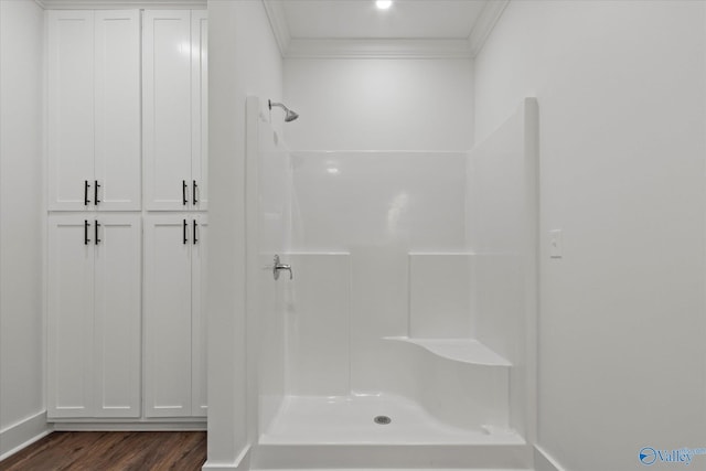 bathroom featuring a shower, wood finished floors, baseboards, and ornamental molding