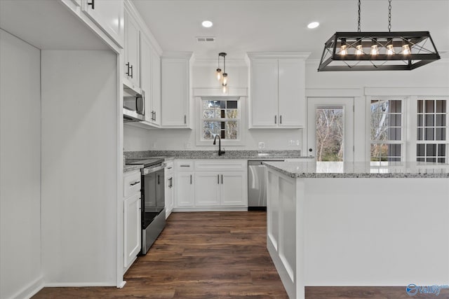 kitchen with a sink, light stone counters, white cabinets, and appliances with stainless steel finishes