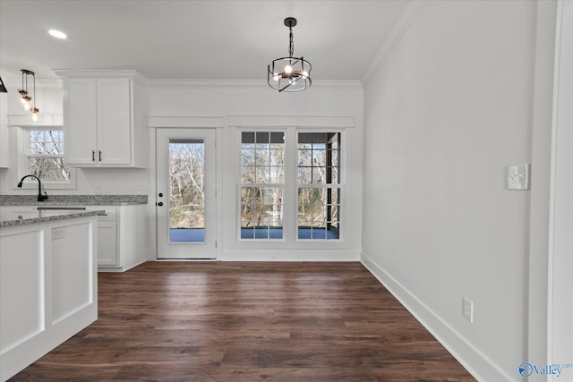unfurnished dining area with recessed lighting, baseboards, dark wood-style flooring, ornamental molding, and a sink