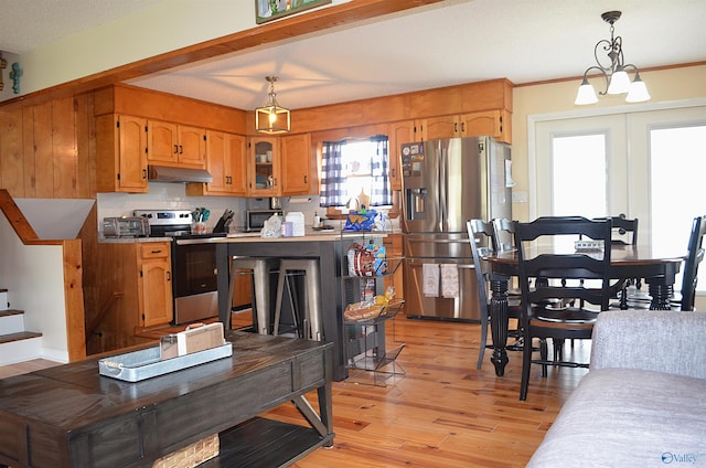 kitchen featuring pendant lighting, light hardwood / wood-style floors, appliances with stainless steel finishes, and a chandelier