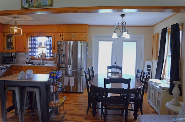 dining space featuring french doors, crown molding, sink, a notable chandelier, and light hardwood / wood-style floors