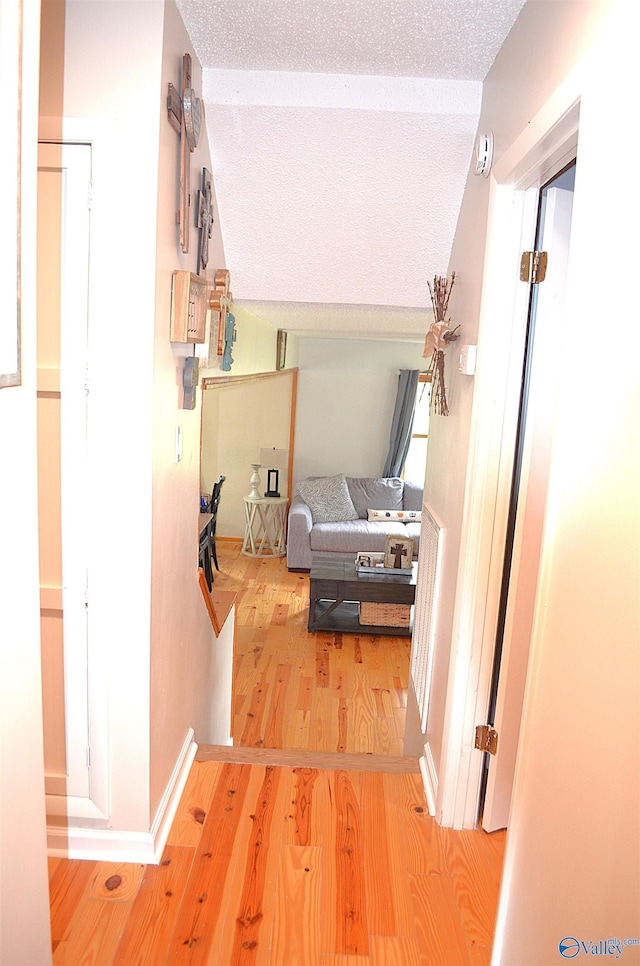 hall featuring wood-type flooring and a textured ceiling