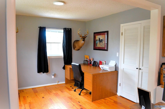 office with light hardwood / wood-style flooring and a textured ceiling