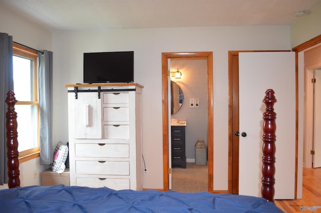 bedroom featuring light wood-type flooring and connected bathroom