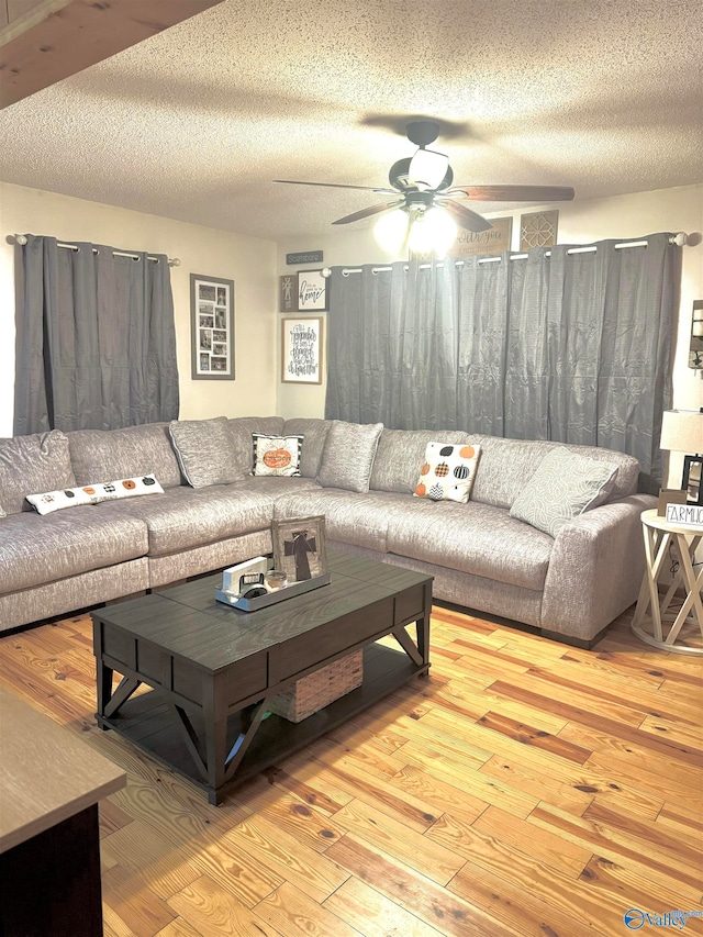 living room featuring a textured ceiling, light wood-type flooring, and ceiling fan