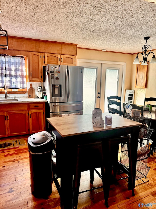 dining area with french doors, a textured ceiling, light hardwood / wood-style flooring, and sink