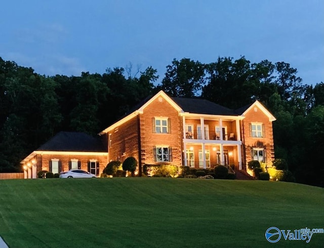 colonial-style house featuring a front yard, a balcony, and an attached garage