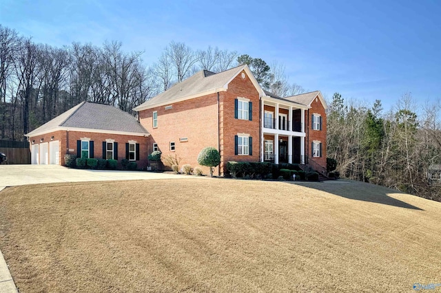 view of front of home with a front lawn, a balcony, and driveway