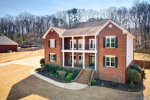 view of front of house featuring driveway, a porch, fence, a balcony, and brick siding