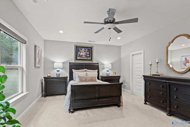 bedroom with multiple windows, ceiling fan, and light carpet