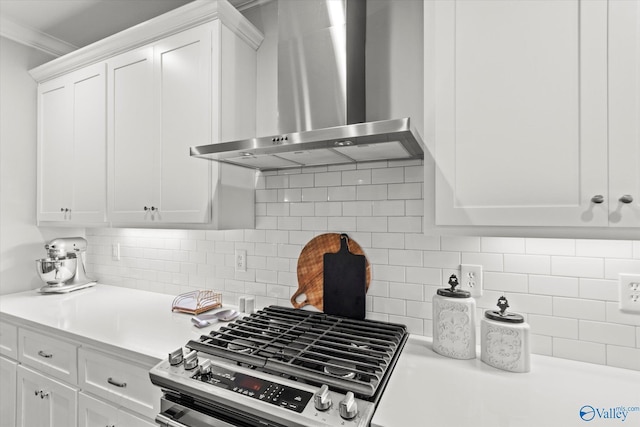 kitchen with crown molding, wall chimney exhaust hood, stainless steel range, tasteful backsplash, and white cabinetry