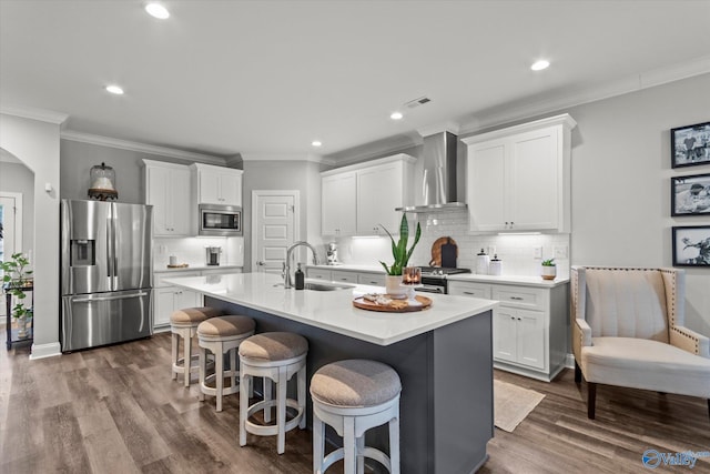 kitchen featuring sink, stainless steel appliances, white cabinetry, and wall chimney range hood