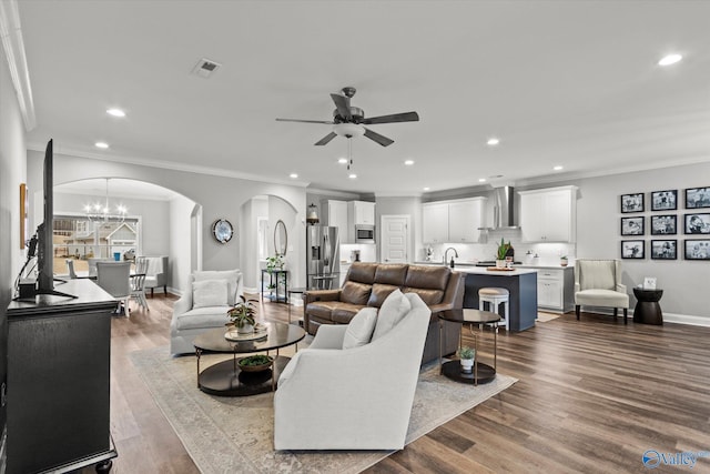 living room with crown molding, sink, light hardwood / wood-style floors, and ceiling fan with notable chandelier