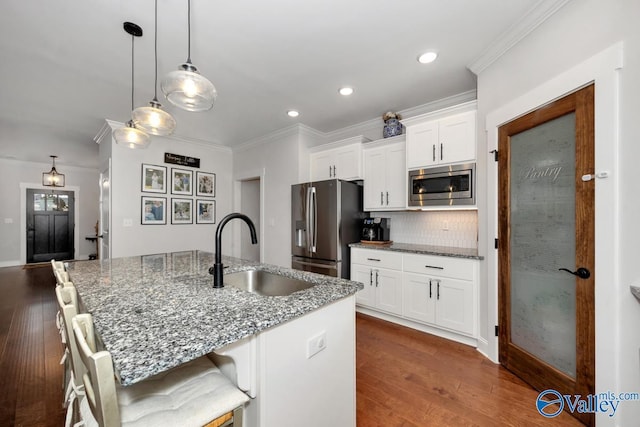 kitchen with stainless steel appliances, white cabinets, a sink, and dark stone countertops