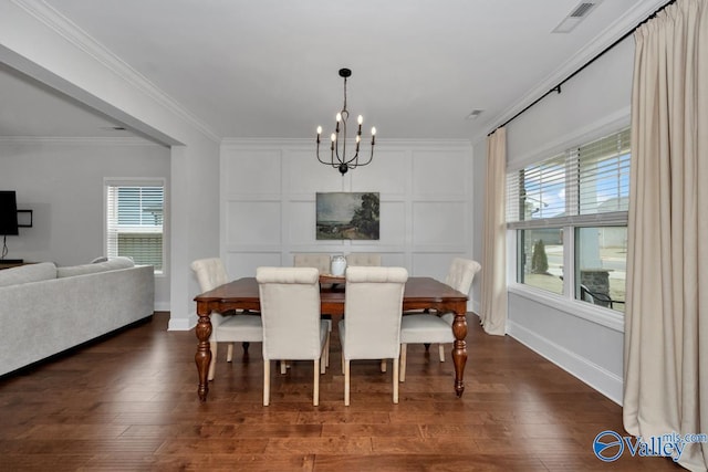 dining area featuring ornamental molding, dark wood-type flooring, an inviting chandelier, and a decorative wall