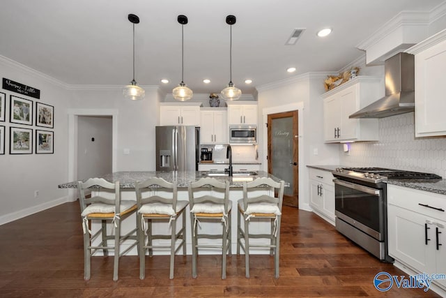 kitchen with white cabinets, an island with sink, wall chimney exhaust hood, dark stone countertops, and stainless steel appliances