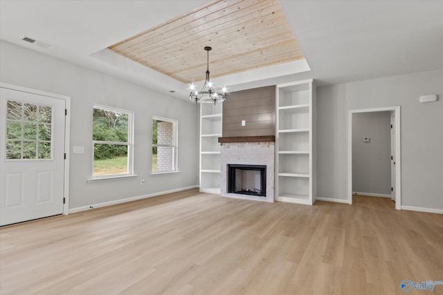 unfurnished living room featuring light hardwood / wood-style flooring, a tray ceiling, wooden ceiling, a chandelier, and a fireplace