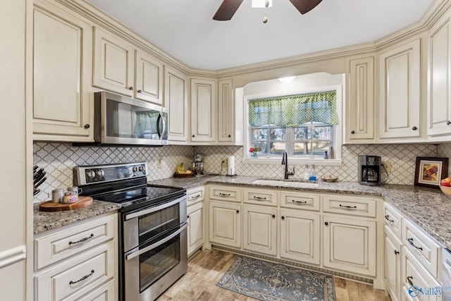 kitchen featuring cream cabinetry, decorative backsplash, light wood-type flooring, and stainless steel appliances