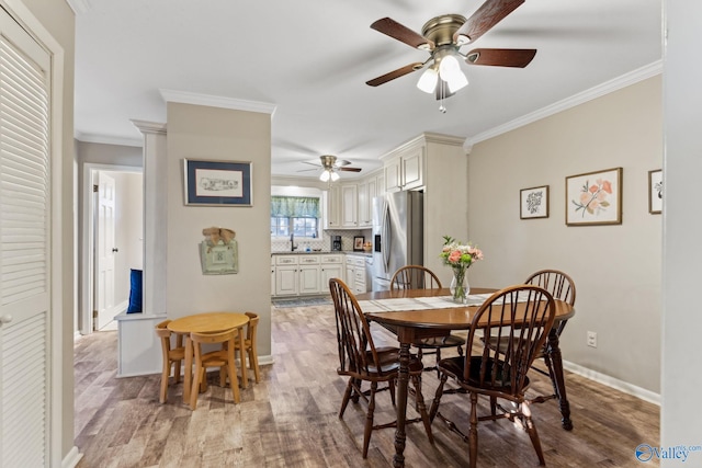 dining area with light wood-type flooring, ceiling fan, and crown molding