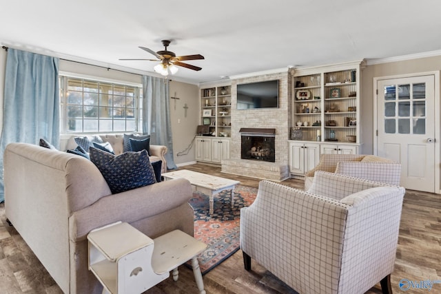 living room with hardwood / wood-style flooring, built in features, ornamental molding, and a fireplace