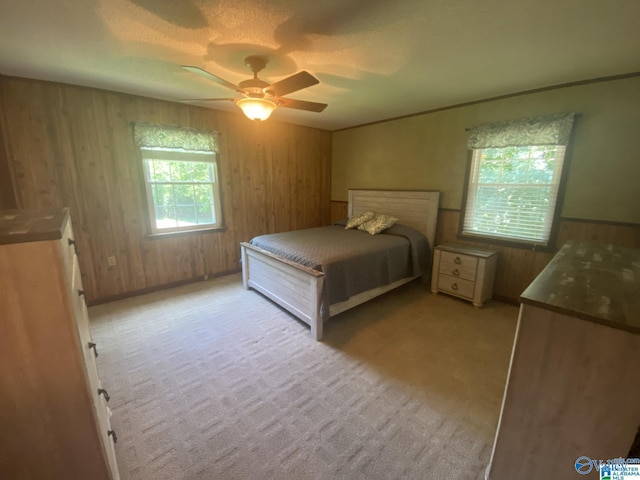 bedroom with multiple windows, ceiling fan, and wooden walls