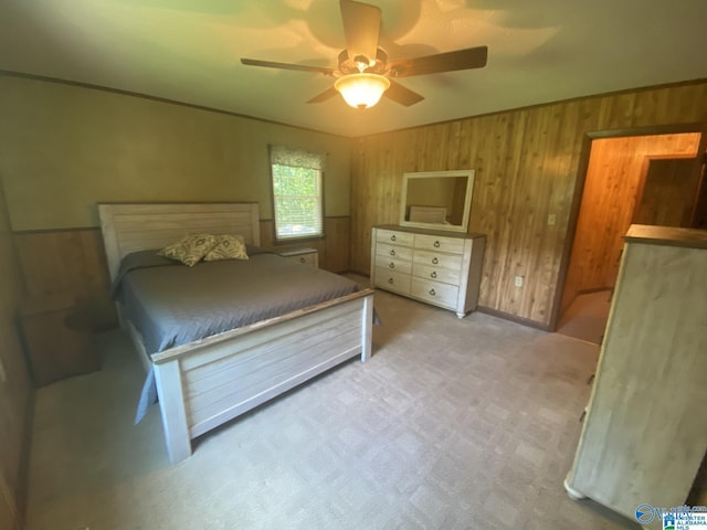 carpeted bedroom featuring ceiling fan and wooden walls