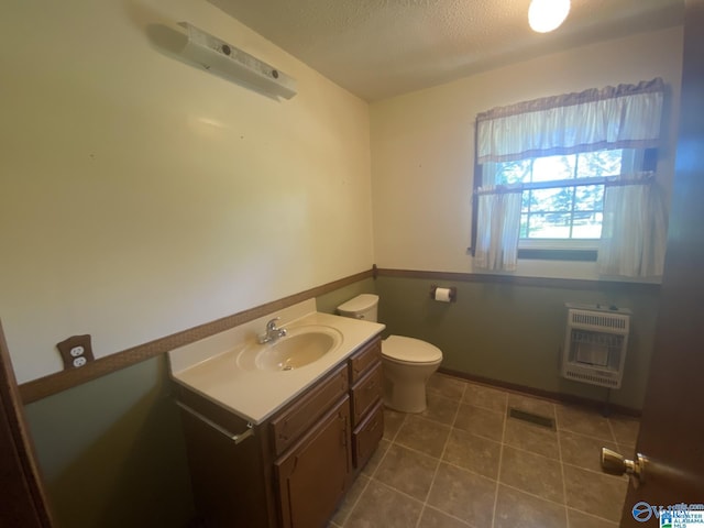 bathroom featuring vanity, tile patterned floors, toilet, a textured ceiling, and heating unit