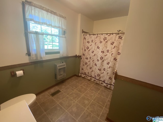 bathroom featuring a shower with curtain, heating unit, and toilet