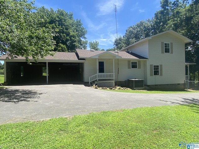 view of front of house with a front lawn, central AC, and a carport