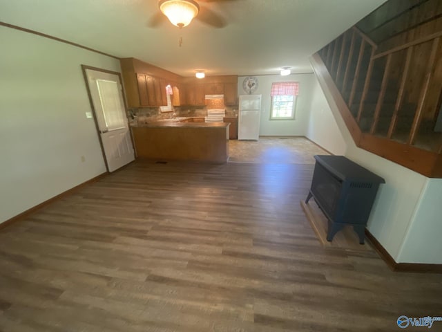 kitchen featuring a wood stove, ceiling fan, dark wood-type flooring, tasteful backsplash, and white refrigerator