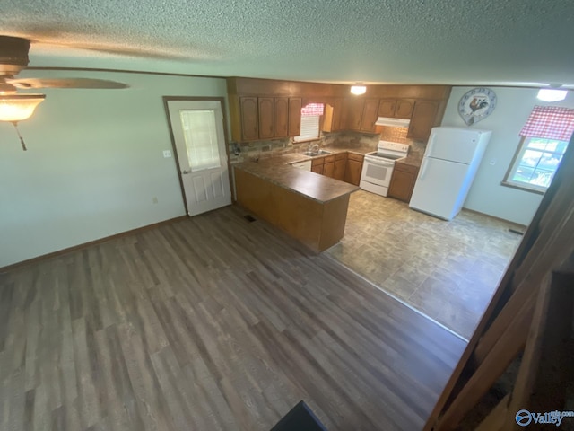 kitchen featuring white appliances, decorative backsplash, ceiling fan, a textured ceiling, and kitchen peninsula