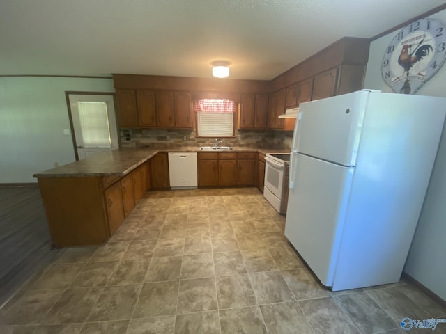 kitchen with kitchen peninsula, white appliances, backsplash, and sink