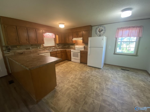 kitchen featuring kitchen peninsula, decorative backsplash, white appliances, and sink